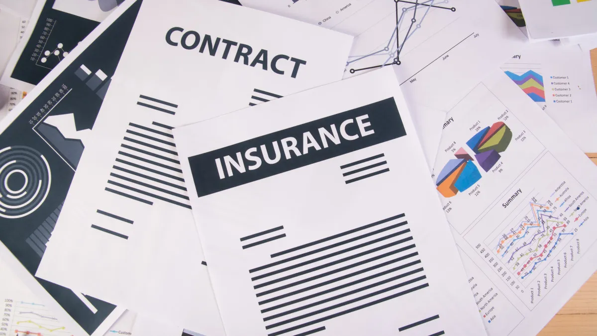 Un tas de papiers posé sur une table avec un contrat d'assurance